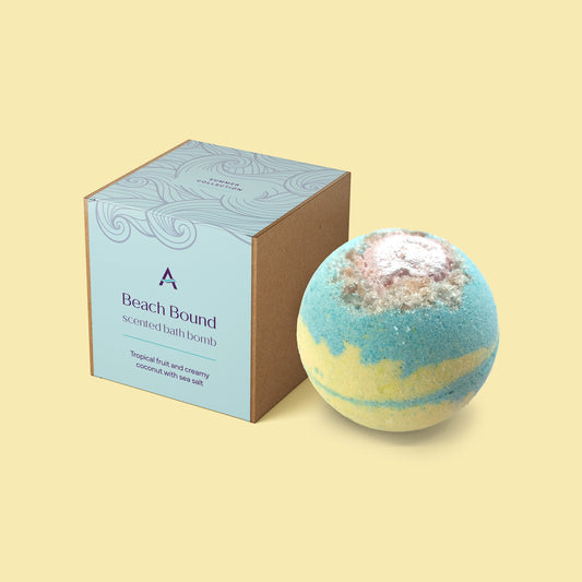 Blue and yellow Beach Bound bath bomb with pink shell topper and tropical scent.